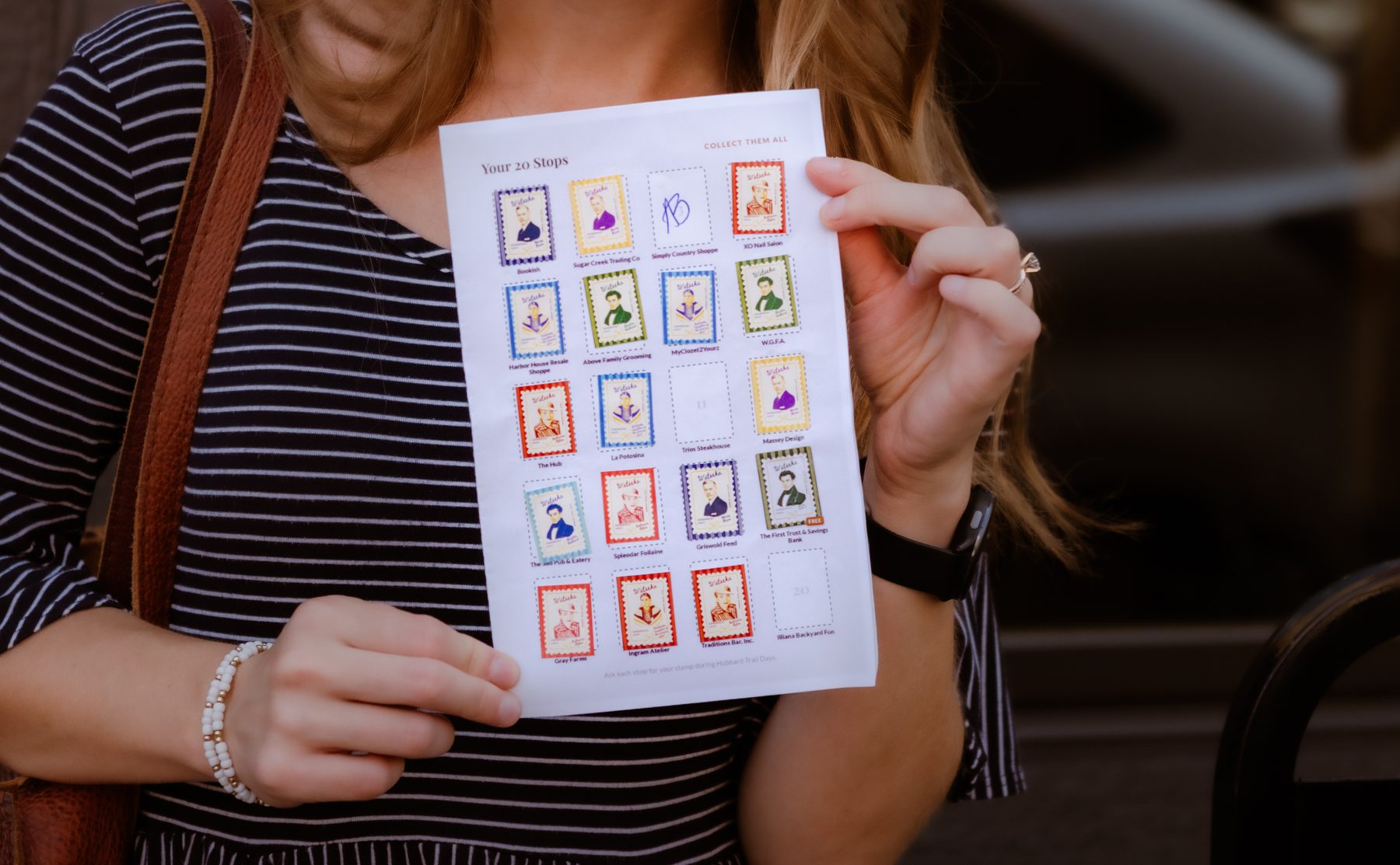 A visitor holding up a Hubbard Trail Days passport filled with collected stamps